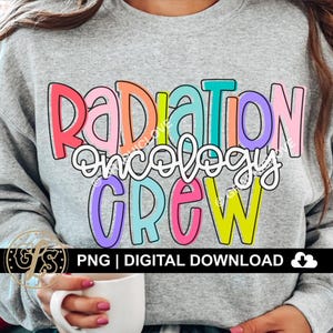 Może przedstawiać: Jasnoszara bluza z napisem "RADIATION ONCOLOGY CREW" w kolorowych, obrysowanych literach. Tekst jest w zabawnej czcionce. Poniżej tekstu znajduje się "PNG | DIGITAL DOWNLOAD".