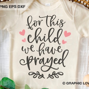 Puede incluir: Un body blanco con el texto "for this child we have prayed" en letras negras. Hay corazones rosas alrededor del texto y un diseño floral en la parte inferior. El texto "GRAPHIC LOVE SVG" está en la esquina inferior derecha.