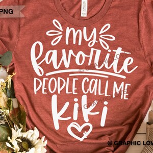 May include: A rust-colored t-shirt with white text that reads "My favorite people call me Kiki" with a white heart underneath the text.