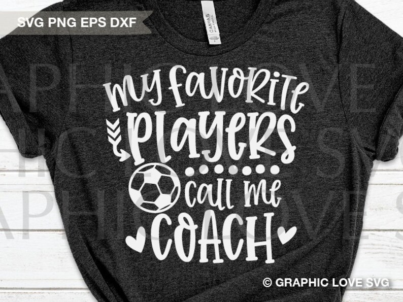 May include: A dark gray t-shirt with white text that reads "My favorite players call me coach" with a soccer ball graphic and hearts.