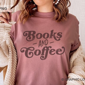 Può includere: T-shirt rosa antico con la scritta "Books and Coffee" in marrone, con un font retrò. La maglietta è indossata con un cardigan color crema. Il tema generale è la lettura e il caffè.