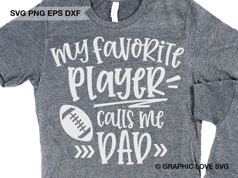 May include: Gray t-shirt with white text that reads "my favorite player= calls me DAD" with a white football graphic. The text is in a handwritten font.