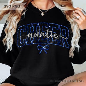 May include: Black sweatshirt with the words "CHEER auntie" in blue glitter lettering. A blue glitter bow is at the bottom. The text "SVG PNG" is in the top left corner.