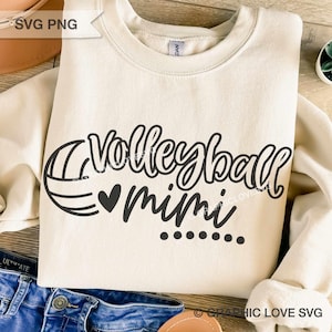 May include: Cream-colored sweatshirt with the words "Volleyball Mimi" in a black script font, accompanied by a volleyball graphic and a heart. The design includes six dots below the word "mimi".