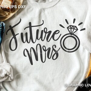 May include: White sweatshirt with the text "Future Mrs." in black cursive lettering and a black ring with a diamond graphic.