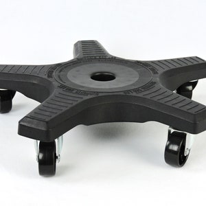 May include: Black plastic plant stand with five points and four wheels. The stand has a circular center with a hole in the middle. The text "Supports up to 100 lbs" is printed on the stand.