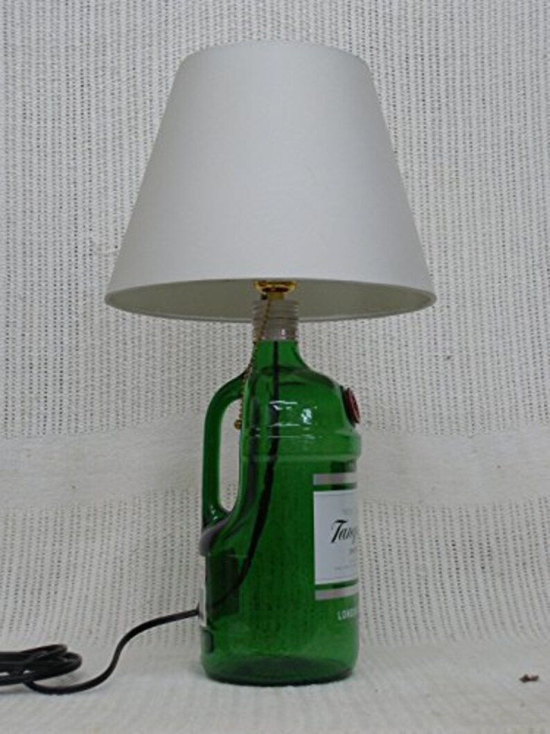 May include: A green glass bottle lamp with a white lampshade. The bottle has a label that says "Tanqueray" and "London Dry Gin".