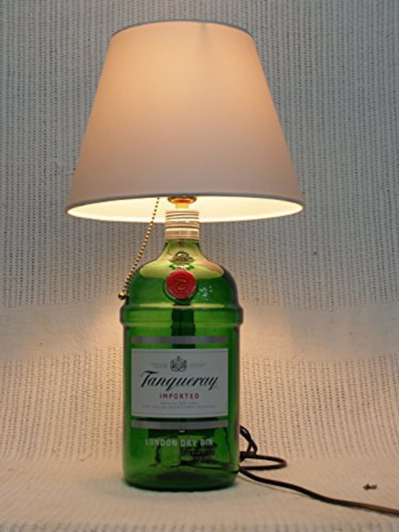 May include: A green glass bottle lamp with a white lampshade. The bottle is labeled "Tanqueray Imported London Dry Gin".