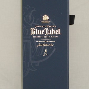 May include: A dark blue box with gold lettering for Johnnie Walker Blue Label Blended Scotch Whisky. The box features a gold anchor and the text "A blend of our rarest whiskies" and "John Walker & Sons".