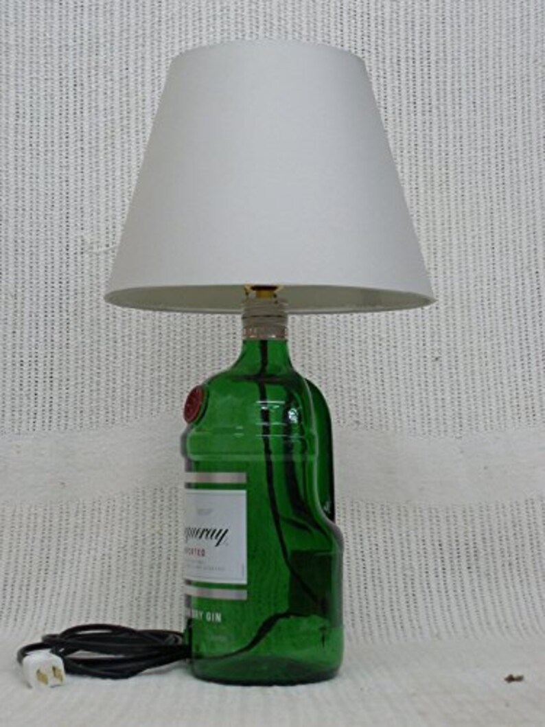May include: A green glass bottle lamp with a white lampshade. The bottle is labeled "Tanqueray" and "London Dry Gin".