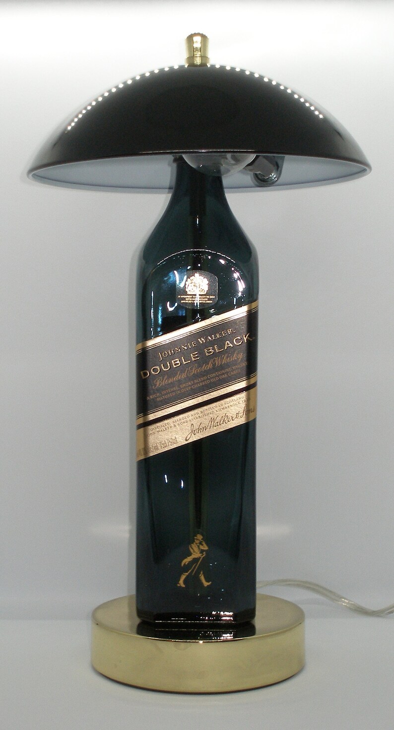 May include: A black lamp with a gold base and a black lampshade. The lamp is made from a repurposed Johnnie Walker Double Black Blended Scotch Whisky bottle.