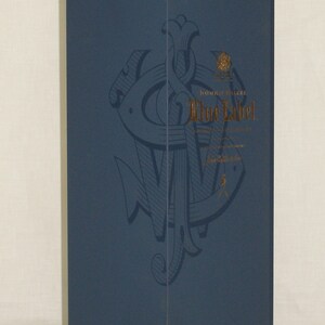 May include: A blue box with a gold logo and the text "Johnnie Walker Blue Label" printed on it. The logo is a stylized anchor with a crown above it.