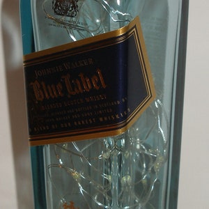 K&ouml;nnte beinhalten: Eine durchsichtige Glasflasche Johnnie Walker Blue Label Blended Scotch Whisky. Die Flasche hat ein goldenes Etikett mit dem Text "Johnnie Walker Blue Label" und "A Blend of Our Rarest Whiskies".