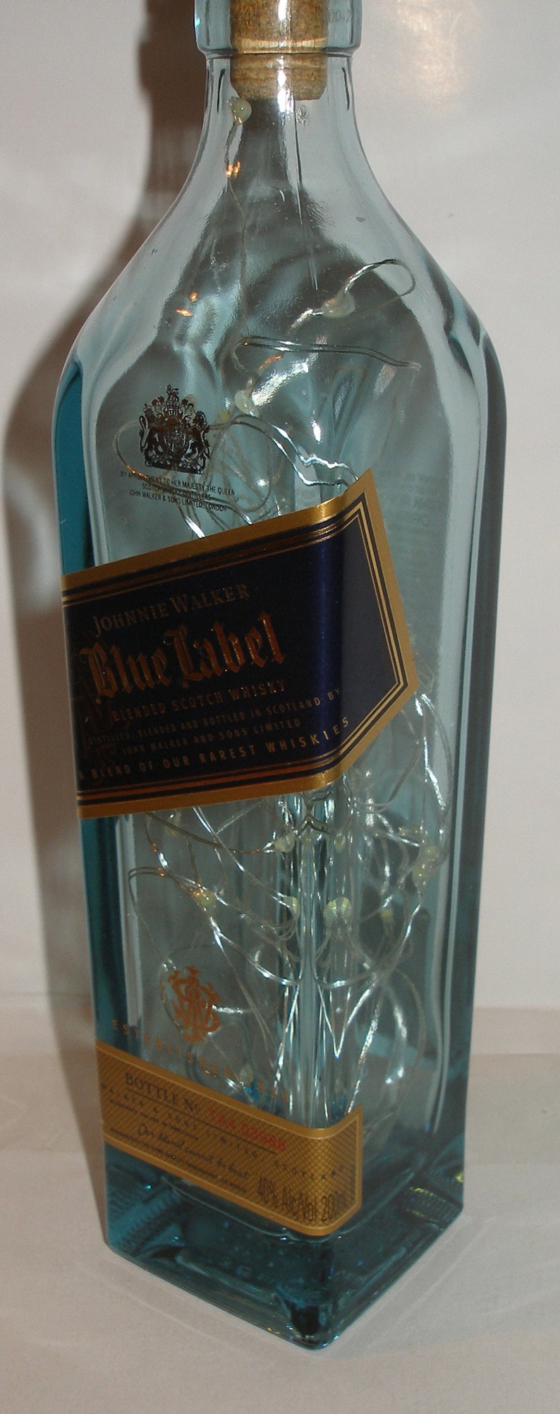 K&ouml;nnte beinhalten: Eine durchsichtige Glasflasche Johnnie Walker Blue Label Blended Scotch Whisky. Die Flasche hat ein goldenes Etikett mit dem Text "Johnnie Walker Blue Label" und "A Blend of Our Rarest Whiskies".