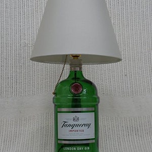 May include: A green glass bottle lamp with a white lampshade. The bottle is labeled "Tanqueray Imported London Dry Gin".