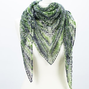 May include: A handmade, open-weave shawl in shades of green, gray, and white, displayed on a mannequin. The triangular shawl features a delicate, lacy pattern, with the colors blending in a gradient effect. The overall design is lightweight and airy.