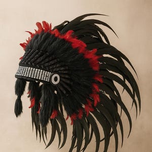 Op de afbeelding: Een Indiaanse hoofdtooi met zwarte en rode veren. De hoofdtooi heeft een zwarte bontbasis met rode accenten en een kralenband. De veren zijn lang en vloeiend, wat een dramatisch effect creëert.