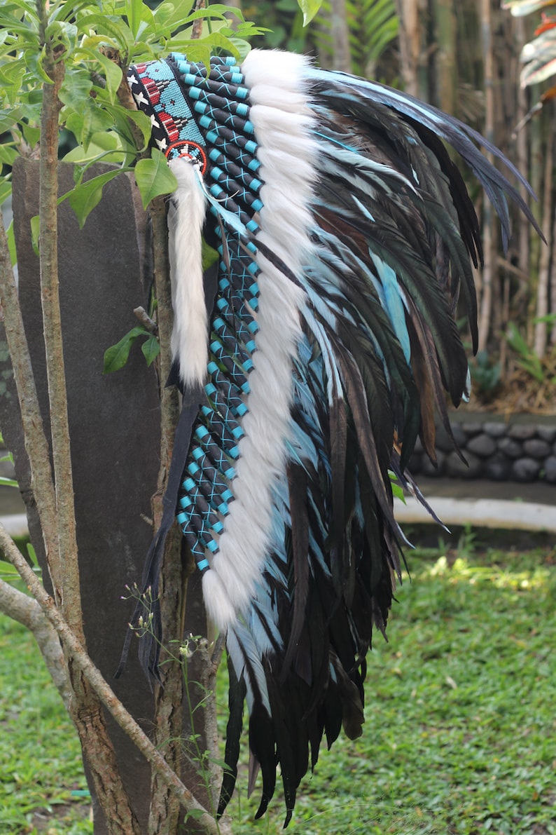 K&ouml;nnte beinhalten: Ein indianischer Kopfschmuck mit schwarzen, wei&szlig;en und blauen Federn. Der Kopfschmuck ist aus Leder und hat ein Band mit Perlen.