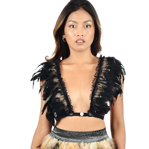 May include: A black lace and feather crop top with a plunging neckline. The top has a black elastic band with a pearl button closure.