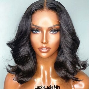 Pode incluir: Uma peruca preta, ondulada, estilo bob com uma frente de renda. A peruca é estilizada com ondas soltas e tem uma linha de cabelo de aparência natural.