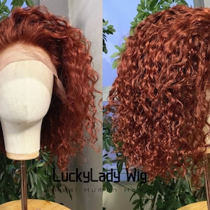May include: A red curly human hair wig on a mannequin head. The wig has a lace front and is styled in a short, layered bob.