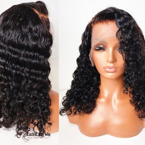 May include: A black human hair wig with loose, curly waves. The wig is styled in a side part and has a lace front. The wig is on a mannequin head.