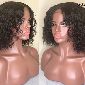 May include: A short, curly, black human hair wig with a lace front. The wig is styled with a side part and is worn on a mannequin head.