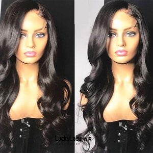 Pode incluir: Uma peruca longa, preta e ondulada de cabelo humano com uma frente de renda. A peruca é estilizada com uma divisão lateral e ondas soltas.