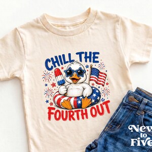 May include: A cream-colored short-sleeve t-shirt featuring a graphic of a duck wearing star-shaped sunglasses, holding a red, white, and blue popsicle, and sitting in a patriotic inner tube. The text reads CHILL THE FOURTH OUT with fireworks.