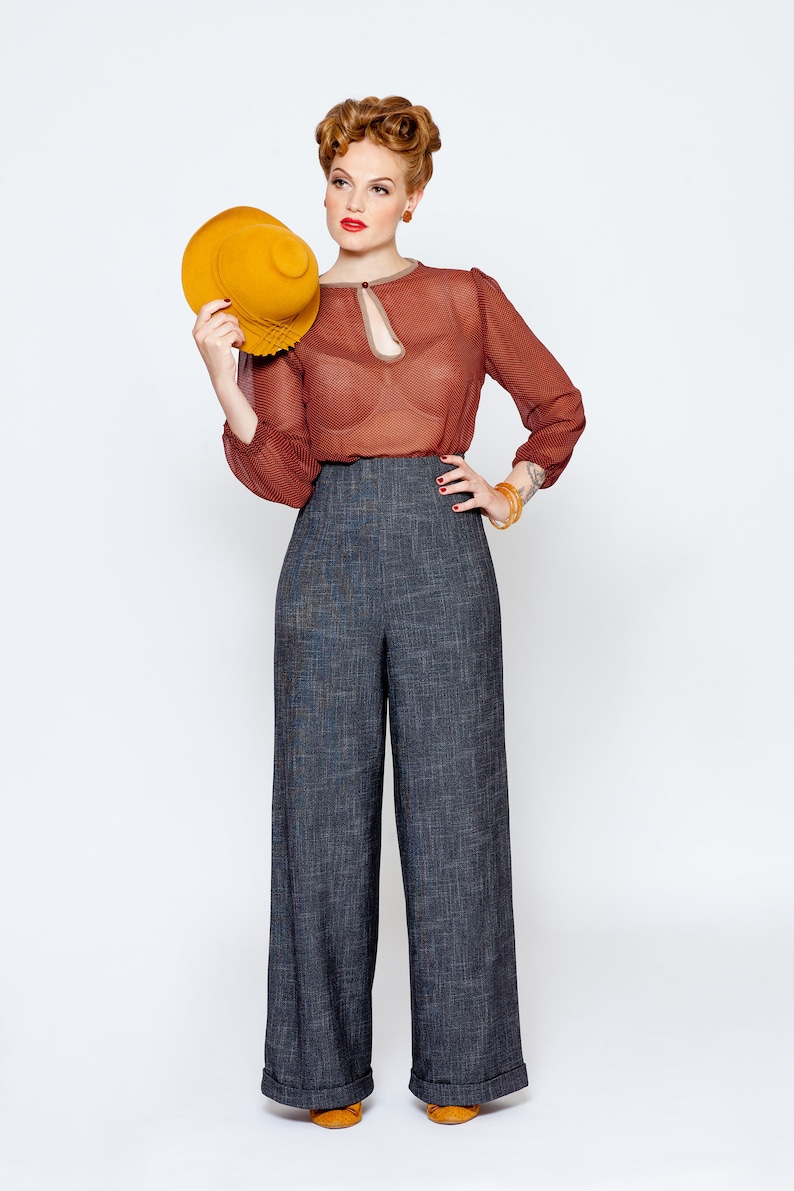 May include: A woman wearing a red sheer blouse with a keyhole neckline, high-waisted wide-leg pants, and a yellow hat.