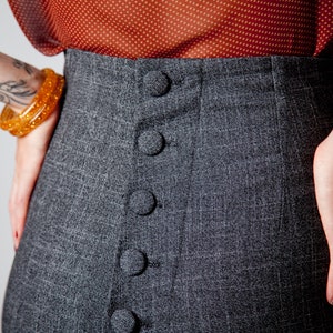 May include: Gray high-waisted pants with a row of five black buttons down the front.