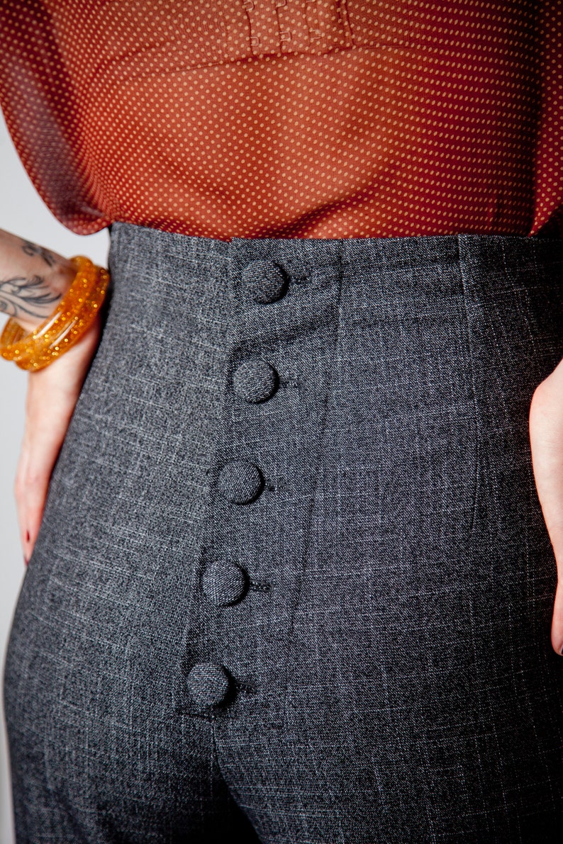 May include: Gray high-waisted pants with a row of five black buttons down the front.