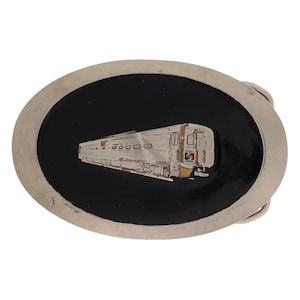 Puede incluir: Hebilla de cinturón ovalada plateada con un centro de esmalte negro. El centro presenta un diseño detallado de tren plateado. La hebilla tiene un estilo clásico y vintage, adecuada para un cinturón.