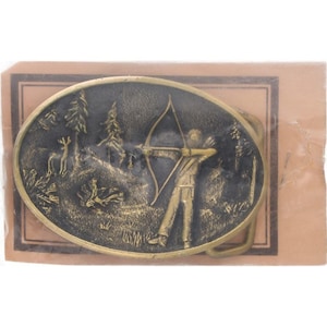 May include: Oval-shaped brass belt buckle featuring an archer aiming a bow and arrow in a forest scene with a deer. The buckle has a detailed relief design and a gold finish. The buckle is in a brown paper package.