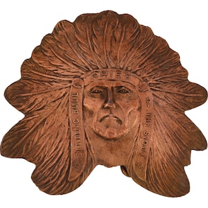 Puede incluir: Una hebilla de cinturón de color cobre con un relieve esculpido de Toro Sentado, jefe de los sioux. La hebilla tiene forma de tocado nativo americano con plumas.