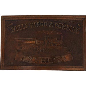 May include: A rectangular, brown metal plaque with the words "WELLS FARGO & COMPANY" at the top. Below is an embossed image of a train and the text "EST. 1852". The word "EXPRESS" is displayed on a banner.