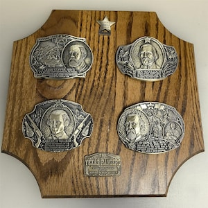 以下が含まれることがあります： 木製のプラークに、肖像画と歴史的なシーンが描かれた4つの銀色のバックルが付いています。バックルは、ジョン・コーヒー・ヘイズ、ベン・マカロック、サミュエル・H・ウォーカー、ローレンス・スル・ロスです。テキサスレンジャーの星と「テキサスレンジャーズ」の小さなプラークも付いています。