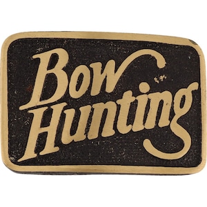 May include: A gold-colored metal belt buckle with the words "Bow Hunting" in a stylized font on a black background.