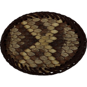 以下が含まれることがあります： 茶色とベージュの革製の楕円形のコースター。ヘビ革模様のデザイン。 コースターは、濃い茶色の編み革の縁取りが施されています。 ヘビ革模様は、明るいタンと濃い茶色の鱗の混合物です。