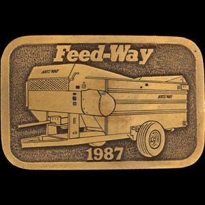 Könnte beinhalten: Rechteckige, goldfarbene Gürtelschnalle mit den Worten "Feed-Way" und "1987" in erhabener Schrift. Die Schnalle zeigt eine detaillierte Illustration einer Landmaschine mit den Worten "Arts-Way".
