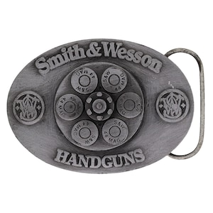 May include: Oval-shaped, silver-colored belt buckle with the words "Smith & Wesson" and "HANDGUNS" embossed. The buckle features a central design of bullets and the Smith & Wesson logo.