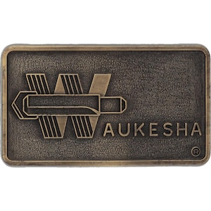 May include: Rectangular bronze-colored metal belt buckle with the word "AUKESHA" in raised lettering. The buckle features a stylized design of a bullet and wings. The overall design has a vintage, industrial aesthetic.
