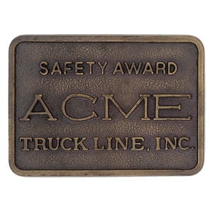 Könnte beinhalten: Rechteckige, bronzefarbene Plakette mit abgerundeten Ecken. Der Text "SAFETY AWARD" steht oben, darunter in großen Buchstaben "ACME". Die Worte "TRUCK LINE, INC." stehen unten. Die Plakette hat eine strukturierte Oberfläche.