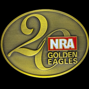 Puede incluir: Una hebilla de cinturón dorada con el número 20 y el texto "NRA Golden Eagles" en letras rojas y blancas.