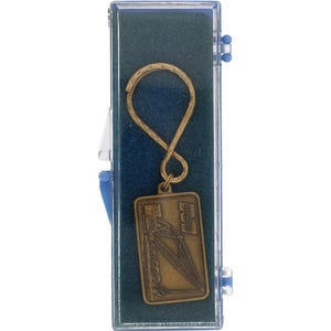 Könnte beinhalten: Ein goldfarbener Vintage-Metall-Schlüsselanhänger mit einem rechteckigen Anhänger mit Industriedesign und dem Wort "MARION". Der Schlüsselanhänger befindet sich in einer transparenten Kunststoffbox mit blauem Innenraum.