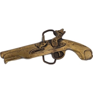 Puede incluir: Una hebilla de cinturón de metal dorado con forma de pistola vintage. La hebilla tiene detalles intrincados y un acabado desgastado y antiguo.