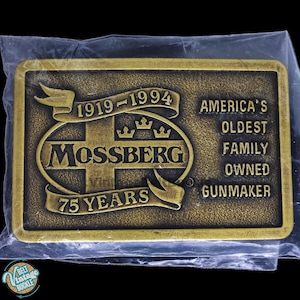 以下が含まれることがあります： モスバーグのロゴと「1919-1994 75 Years America's Oldest Family Owned Gunmaker」の文字が刻まれた、金色調のベルトバックルです。