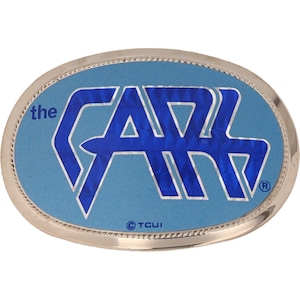 May include: A silver oval belt buckle with a blue background and the words "the CARS" in blue lettering. The buckle has a textured surface and a copyright symbol with the letters "TCUI".