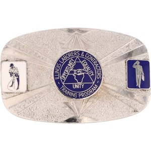 Op de afbeelding: Zilveren gesp met een blauw en wit embleem. Het embleem heeft een driehoek met de woorden "Opportunity", "Equality" en "Unity" erin. De woorden "Illinois Laborers & Contractors - Training Program" omringen de driehoek.