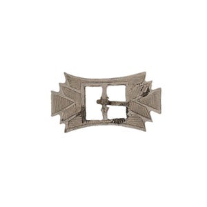 May include: A silver-colored metal buckle with a rectangular center and decorative, leaf-like designs on the ends. The buckle has a slightly curved shape and appears to be vintage or antique.
